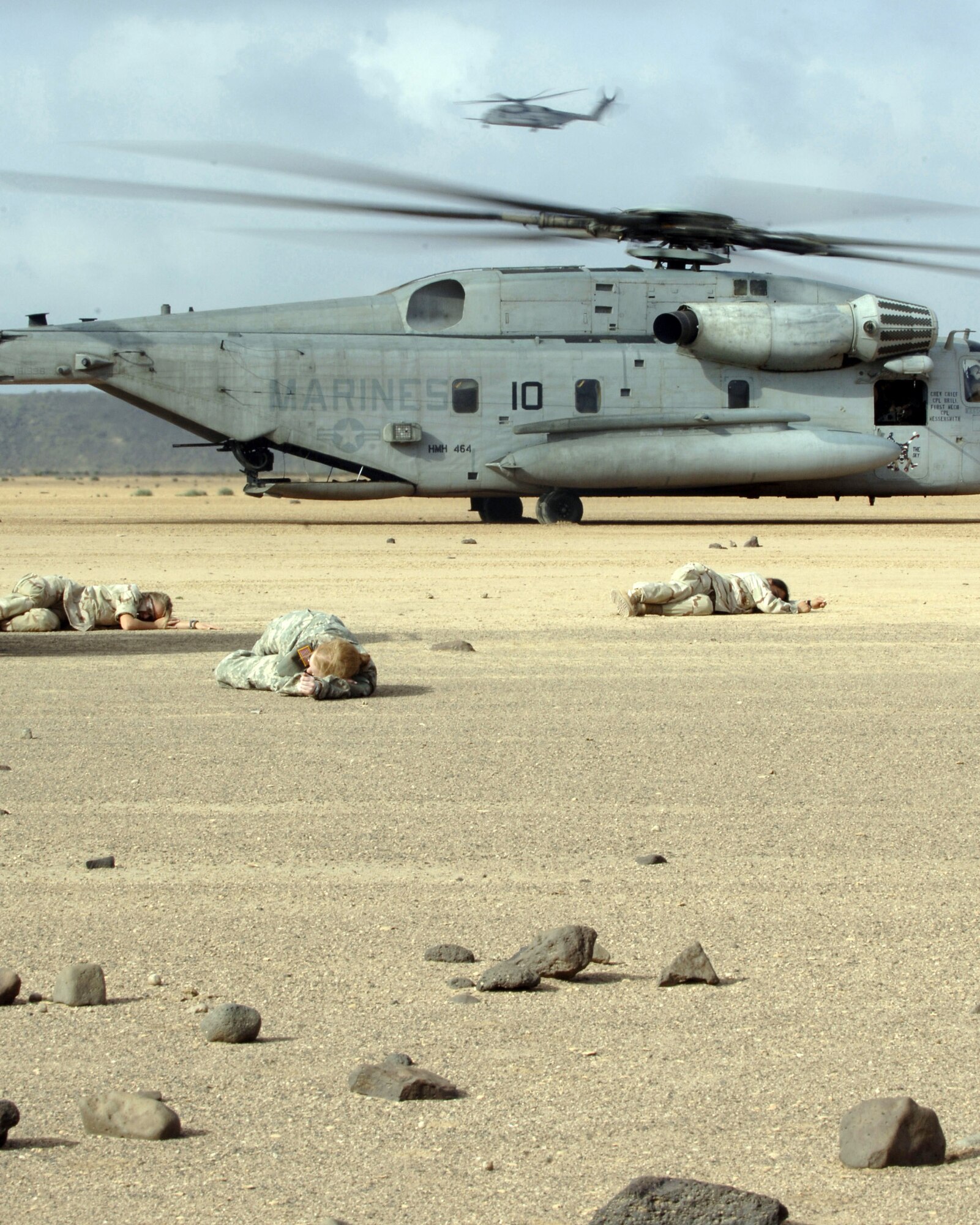 CAMP LEMONIER, DJIBOUTI, Africa (AFPN) -- U.S. military members lay on the ground simulating a car crash injury, while Air Force pararescuemen in a Marine CH-53 Super Stallion helicopter prepare to pick them. The scenario was part of a search and rescue exercise here Feb 8. (U.S. Air Force photo by Staff Sgt. Ricky A. Bloom)
