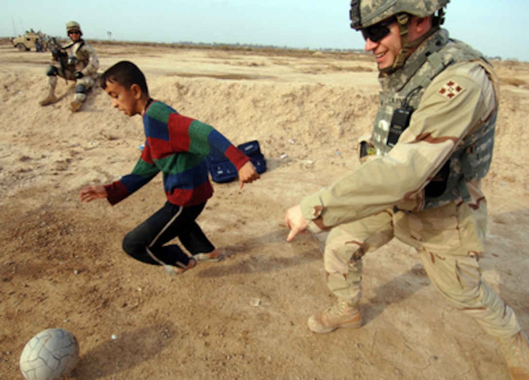 Army Sgt. Jason Layne plays soccer with an Iraqi boy during a visit to the town of Istaqal, Iraq, on Feb. 12, 2006. U.S. Army soldiers with the 1st Battalion, 66th Battalion, 4th Infantry Division, are visiting Istaqal to discuss current economic and health issues with the local populous. 