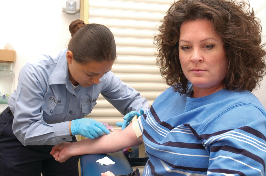 Seaman Yadira Castillo, laboratory technician, Branch Medical Clinic, draws blood from Patricia Geary at the station clinic Feb. 15. Technicians at the laboratory are responsible for blood withdrawal, running complete blood counts, urine analysis and rapid strep test. Sailors have to go through a 13- month training course in order to become certified technicians. ical laboratory technician and overall laboratory supervisor, Branch Medical Clinic, inserts a blood sample into the complete- blood-count machine for analysis at the station?s clinic Feb. 15.