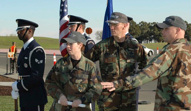 Staff Sgt. Sarah Earp and Staff Sgt. Bradley Swanson, 60th Air Mobility Wing protocol, five an update to Col. Timothy Zadalis, 60th AMW acting commander, on the sequences of events for thefirst Travis Quarterly Reenlistment Ceremony held at the Airman's Wall Jan. 20.