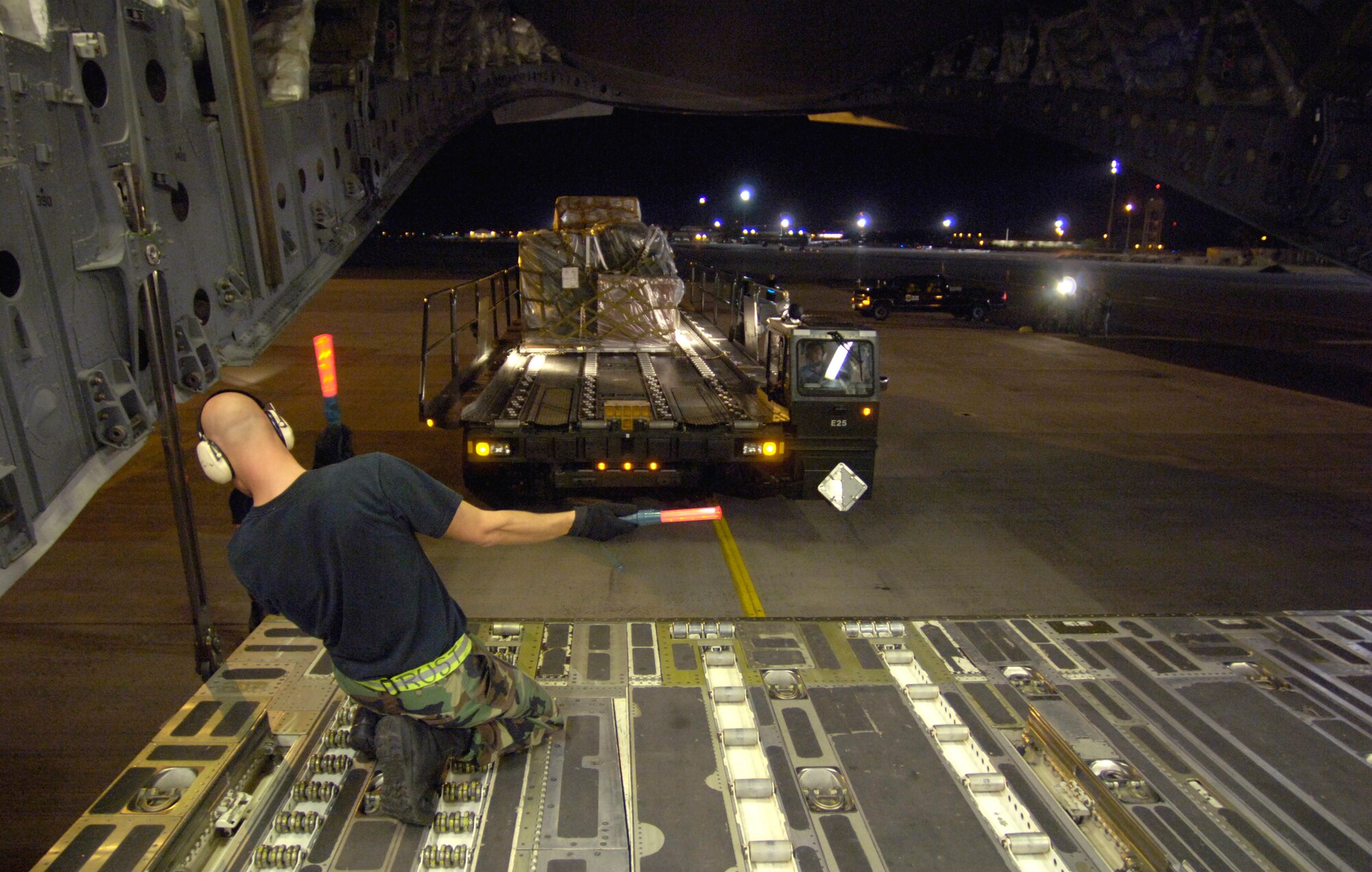 HICKAM AIR FORCE BASE, Hawaii (AFPN) -- Staff Sgt. Nathan Rust directs a K-loader to on-load pallets on a C-17 Globemaster III to support relief efforts in the Philippines. The composite C-17 squadron of active duty and Hawaii Air National Guard loaded the pallets Feb. 21 to carry military rations, water, cots, tents and personnel from the 15th Airlift Wing to help out with the mudslide disaster. Sergeant Rust is from the 735th Air Mobility Squadron at Hickam AFB, Hawaii. (U.S. Air Force photo by Tech. Sgt. Shane A. Cuomo)
