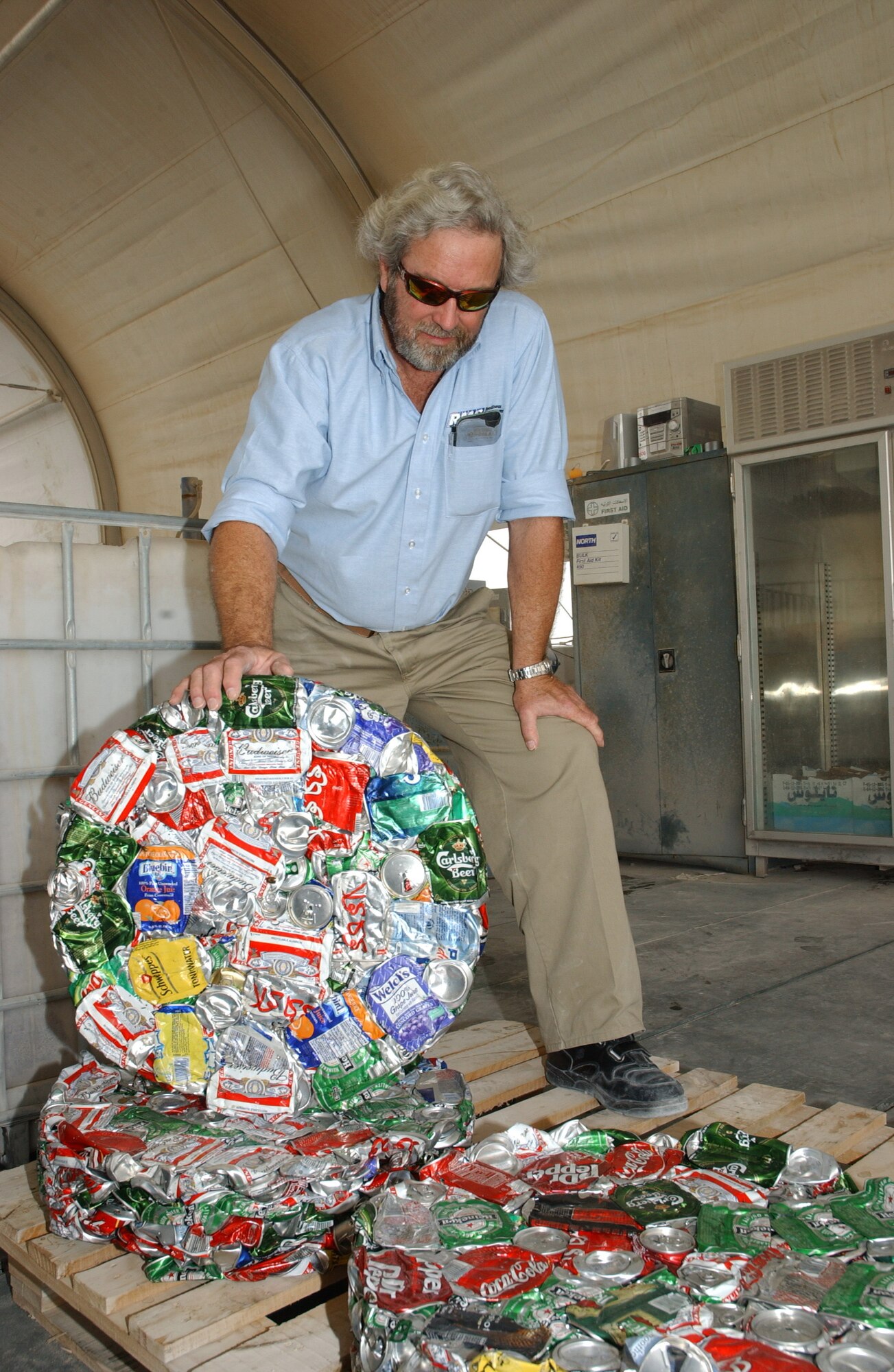 SOUTHWEST ASIA (AFPN) -- Jerry Collier, the base recycling manager, displays a crushed set of cans nicknamed a biscuit. A 55-gallon drum filled with cans can be compressed into four inches worth of aluminum. (U.S. Air Force photo)

