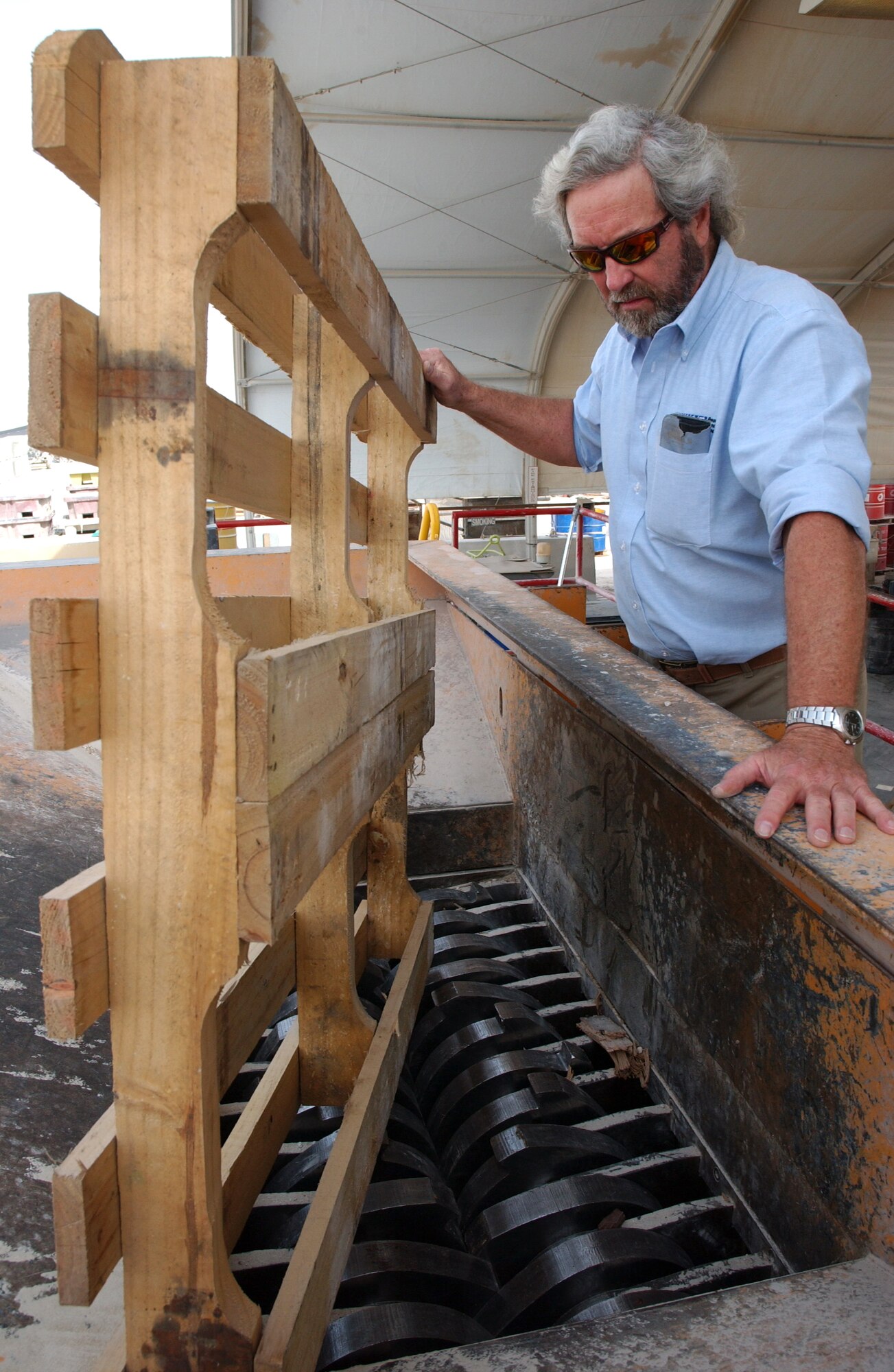 SOUTHWEST ASIA (AFPN) -- Jerry Collier, the base recycling manager, demonstrates where an old pallet is shredded before it's sent to a landfill. (U.S. Air Force photo)
