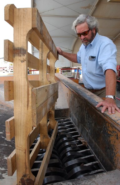 SOUTHWEST ASIA (AFPN) -- Jerry Collier, the base recycling manager, demonstrates where an old pallet is shredded before it's sent to a landfill. (U.S. Air Force photo)