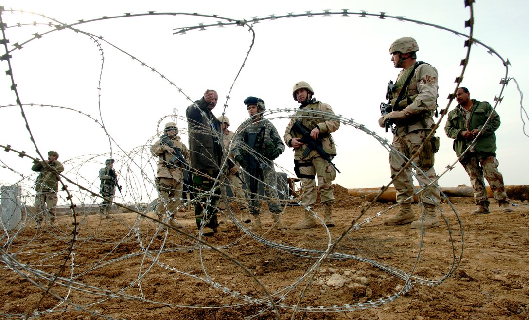 KIRKUK, Iraq (AFPN) -- Lt. Col. Thomas Brown (center) and Tech. Sgt. Billy Tramel (right) speak to Iraqi pipeline protection officers at a canal crossing. They talked about recent damage to the pipeline and security challenges. Colonel Brown is commander of the 732nd Expeditionary Civil Engineer Squadron. Sergeant Tramel is a member of the squadron's petroleum oil and infrastructure team, or POInT. (U.S. Air Force photo by Master Sgt. Lance Cheung)
