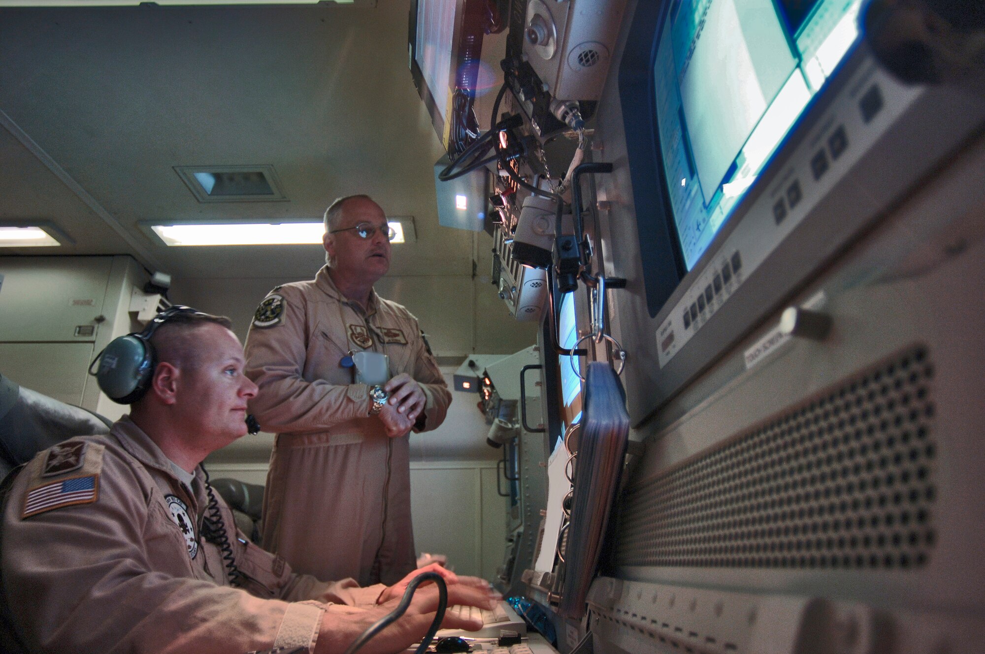 SOUTHWEST ASIA (AFPN) -- Lt. Col. Jim Roman (right), talks with Army Sgt. 1st Class Steven Jamie about the timing of communications to Army ground units. Colonel Roman is the mission crew commander is in charge of the mission crew and decisions made aboard this E-8C Joint Surveillance and Target Attack Radar System aircraft. He is responsible for all outgoing communications. Sergeant Jamie is an airborne target surveillance supervisor, is a communicator with Army units and common ground stations, using various radio and satellite communication devices. (U.S. Air Force photo by Master Sgt. Lance Cheung) 