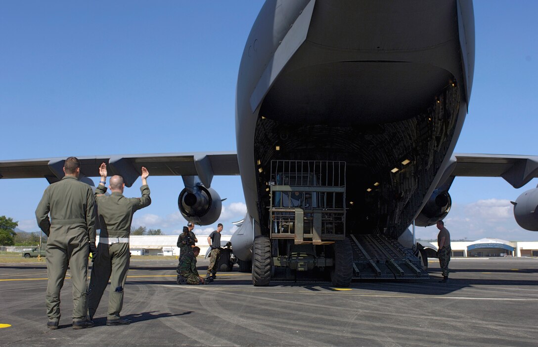 MACTAN AIR BASE, Philippines (AFPN) -- Staff Sgt. Ryan Page and Tech. Sgt. Ken Bragg marshal a forklift off of a C-17 Globemaster III Feb. 22. The composite C-17 squadron of active duty and Hawaii Air National Guard flew their first contingency response mission to deliver relief supplies to the Philippines. The Airmen are with the 535th Airlift Squadron. (U.S. Air Force photo by Tech. Sgt. Shane A. Cuomo)