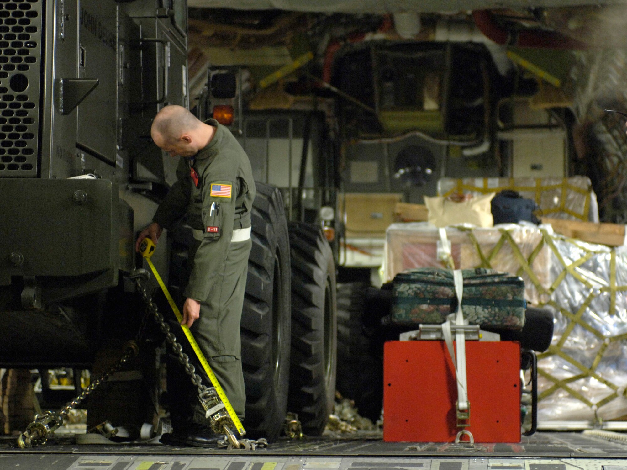 ANDERSEN AIR FORCE BASE, Guam (AFPN) -- Staff Sgt. Ryan Page measures support chains that strap down a forklift on a C-17 Globemaster III Feb. 22. The composite C-17 squadron of active duty and Hawaii Air National Guard flew their first contingency response mission to deliver relief supplies to the Philippines. Sergeant Page is with the 535th Airlift Squadron. (U.S. Air Force photo by Tech. Sgt. Shane A. Cuomo)