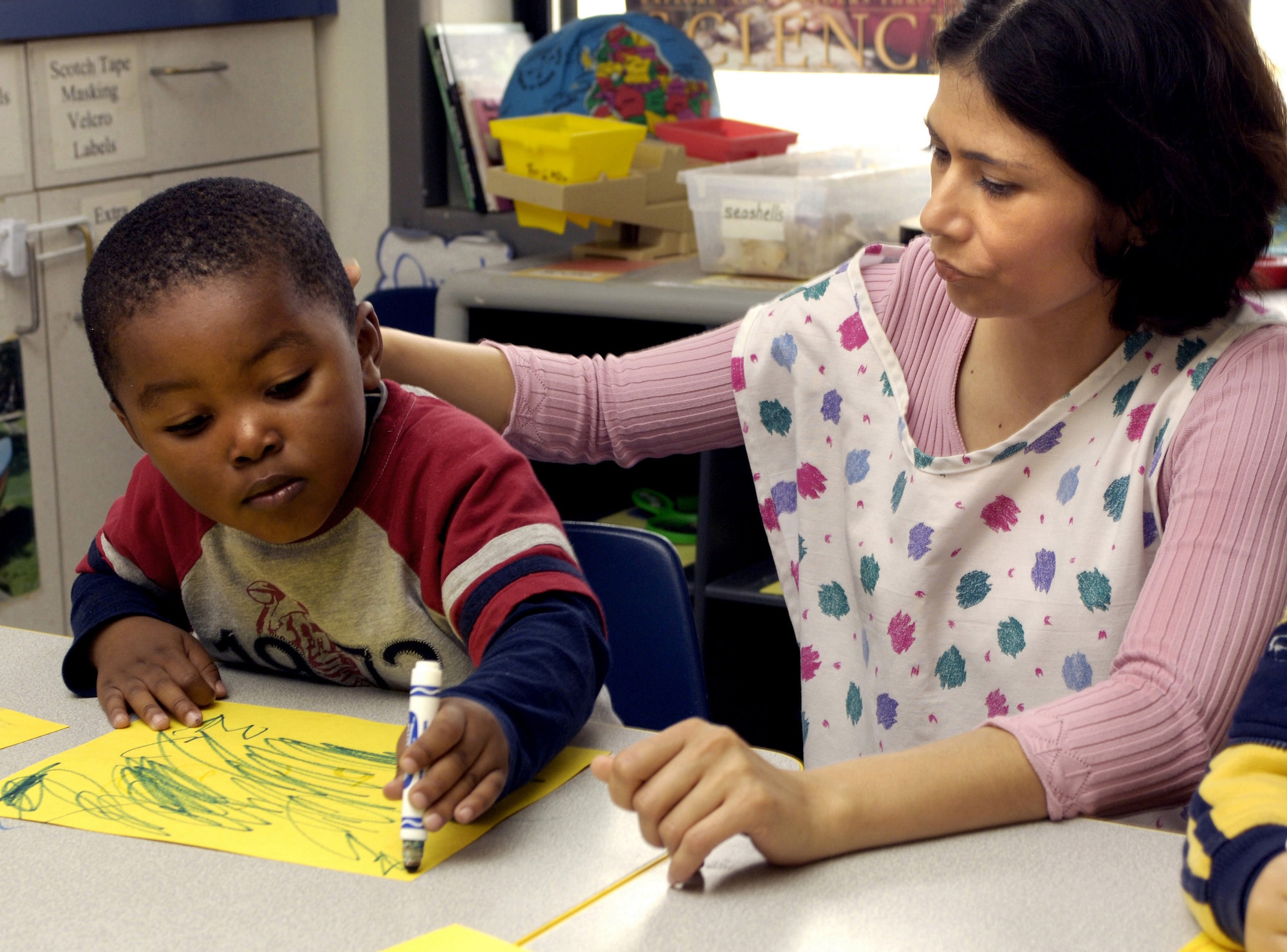 KEESLER AIR FORCE BASE, Miss. (AFPN) -- Yvonte Larosier, 3, draws a picture of flying debris from Hurricane Katrina for Sandra Markland at the child development center Feb. 21. The children's drawings are displayed throughout the center as a means for them to express their feelings about the hurricane. Yvonte's mother is Staff Sgt. Lakeisha Larosier of the 81st Dental Squadron. (U.S. Air Force photo by Tech. Sgt. Larry A. Simmons) 
