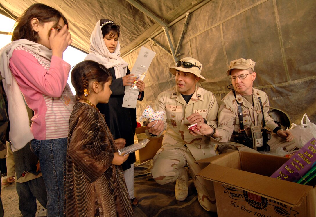 KANDAHAR CITY, Afghanistan (AFPN) -- Maj. David Schlosser and Capt. Craig Lane offer candy and toys to a group of Afghan girls during medical operations at the Shahed Sayed Padsha School Feb. 15. (U.S. Army photo by Spc. Leslie Angulo) 