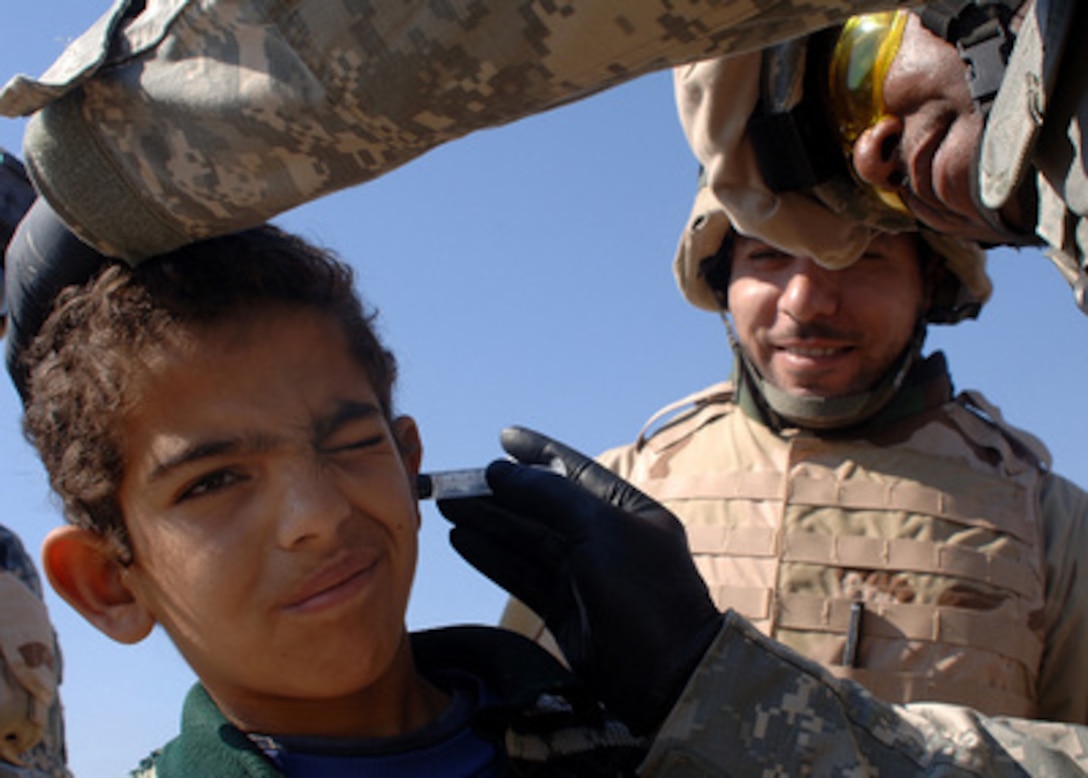 U.S. Army Capt. Edward Barnes treats a six-year-old Iraqi boy for an ear infection during a community health outreach program in Rushadah, Iraq, on Feb. 23, 2006. Barnes is a battalion surgeon for the 66th Armor Battalion, 1st Brigade, 4th Infantry Division. 