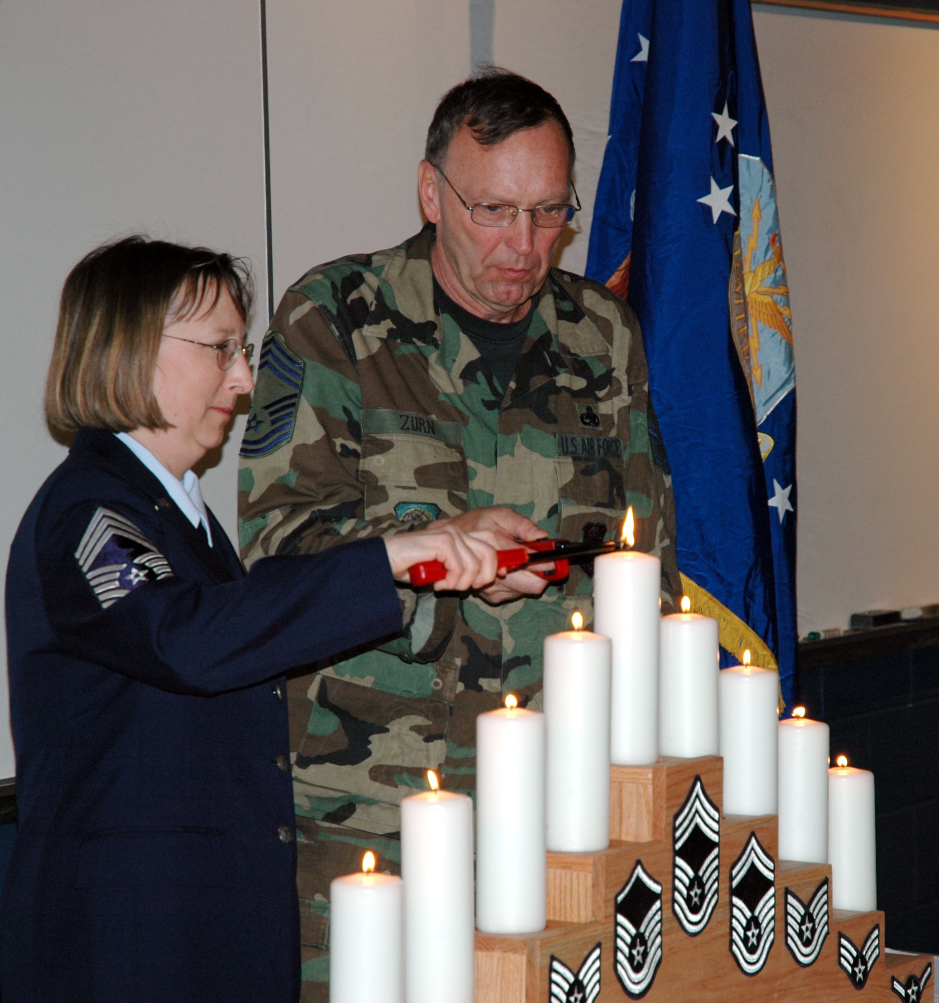 Chief Master Sgt. Lee Traxler-Siehndel as the newest chief and Chief Master Sgt. Michael Zurn, the longest serving chief, jointly light the candle representing their rank at the Air Force Reserve 934th Airlift Wing's first NCO induction. Photo by Tech. Sgt. Jeffrey Williams.  