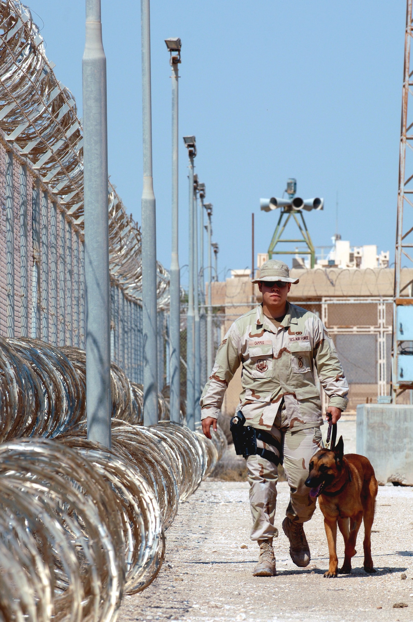 SOUTHWEST ASIA (AFPN) -- Senior Airman Martin Campos patrols the fence line at a deployed location with his military working dog, Rico, Feb. 24. Airman Campos and Rico, a Belgian Malinois, are with the 379th Expeditionary Security Forces Squadron.  (U.S. Air Force photo by Staff Sgt. Joshua Strang)