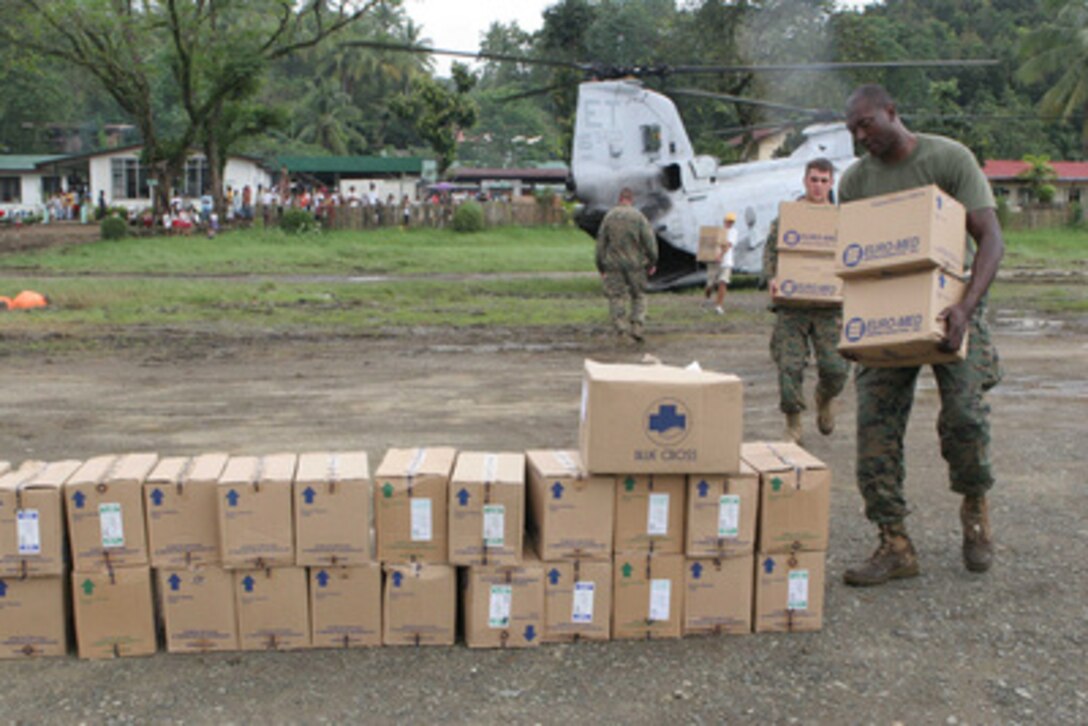 U.S. Marine Staff Sgt. Jimmy Wheeler (right) and Cpl. Joe Rainey unload supplies from a CH-46 Sea Knight helicopter in Saint Bernard, Philippines, on Feb. 21, 2006. The supplies are being delivered in support of humanitarian efforts following the Feb. 17, 2006, landslide in the village of Guinsaugon on the island of Leyte, Philippines. The Marines are attached to 31st Marine Expeditionary Unit. 