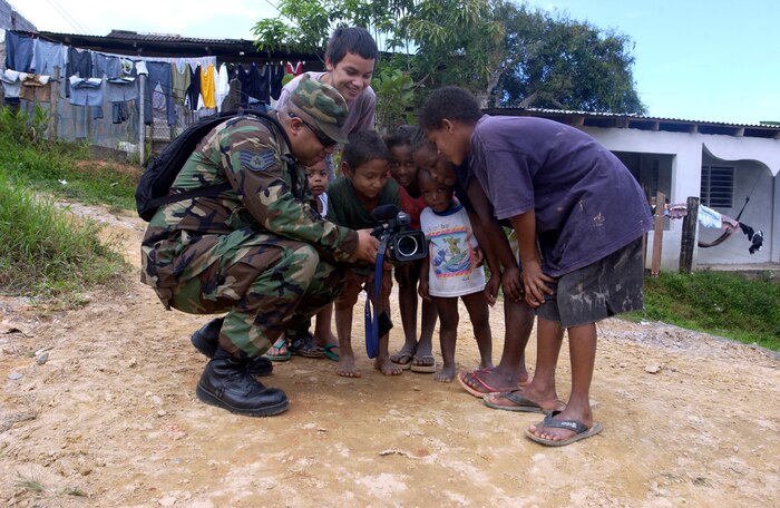 Staff Sgt. Veuril McDavid shows local children images on his video camera's viewfinder at the New Horizons 2006 Gonzales Rivera construction site in Honduras. New Horizons, a $6 million joint U.S.-Honduras military humanitarian exercise, is building four new schools and a maternity ward. In addition, 14 health clinics will provide free medical care to people from the Mosquito Coast through San Pedro Sula. Sergeant McDavid is with the 1st Combat Camera Squadron, Charleston Air Force Base, S.C. (U.S. Air Force photo/Tech. Sgt. Maria J. Bare)