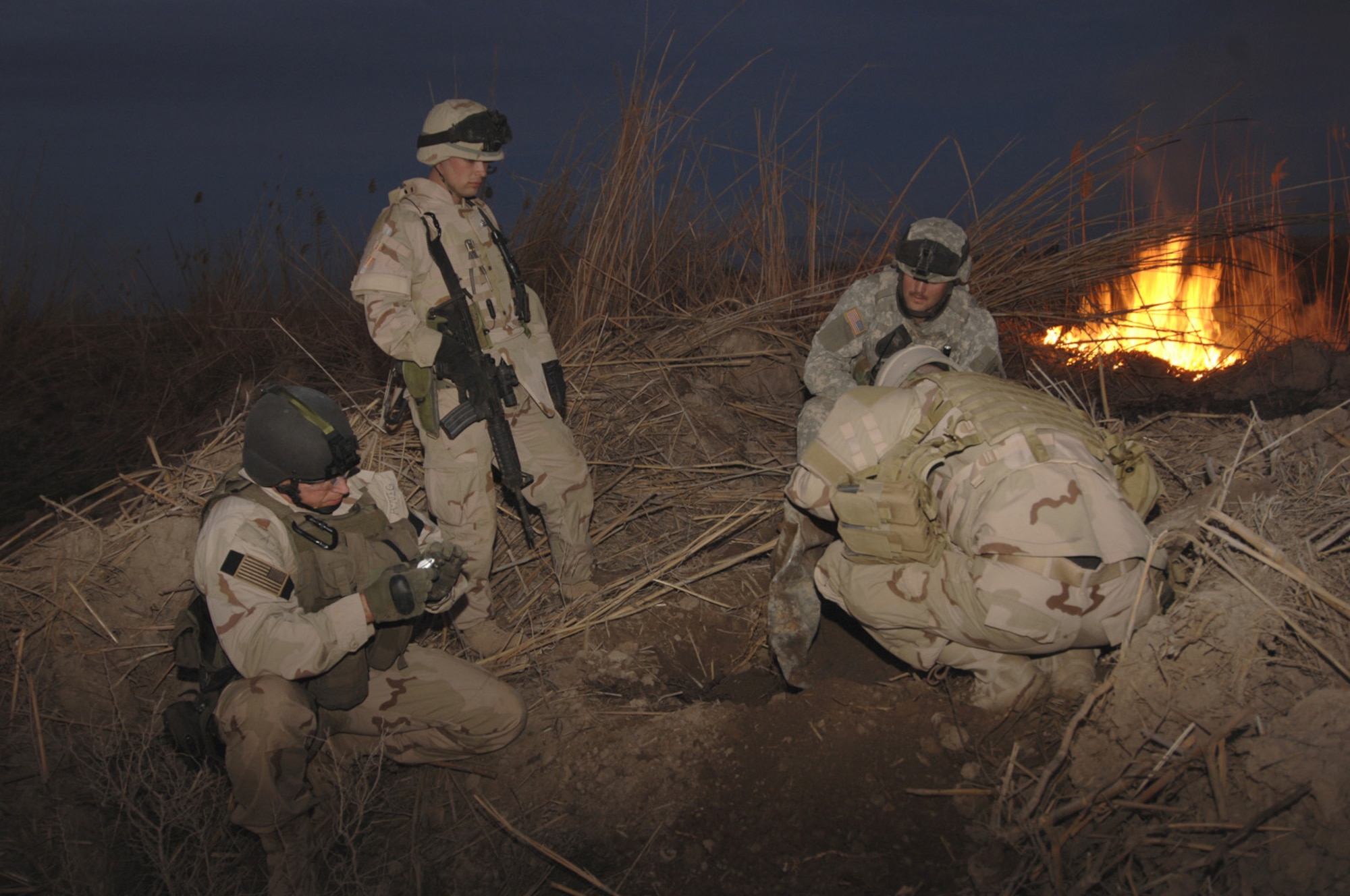 Airmen with the 447th Civil Engineer Squadron's explosive ordnance disposal team explore a munitions bunker in Baghdad, Iraq, Monday, Feb. 20, 2006. The bunker was discovered after a previous detonation scorched the earth, revealing the entrance to a larger weapons cache. (U.S. Navy photo/Petty Officer 2nd Class Samuel Peterson)

