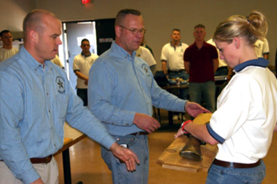 Maj. Walker Field (left) and Sergeant Major Daniel Huff present Sgt. Jillian Linnet with a mounted Winchester M1873 Replica Rifle for being the top performer in the recruiting station's "Texas Shootout" offensive.