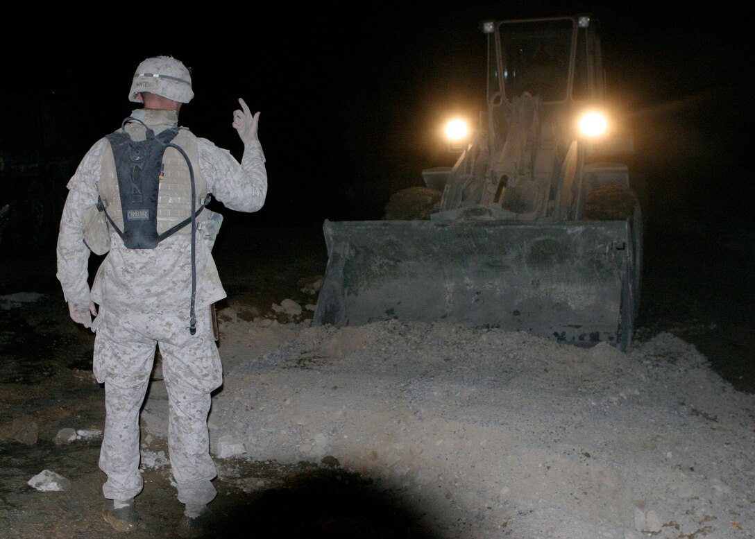 An engineer from MEU Service Support Group 22, the combat service support element of the 22nd Marine Expeditionary Unit (Special Operations Capable), directs a TRAM as it packs gravel into a pothole in a road near Hit, Iraq, Jan. 2, 2006.  The 22nd MEU (SOC) is currently conducting counterinsurgency operations in Iraq's Al Anbar province.