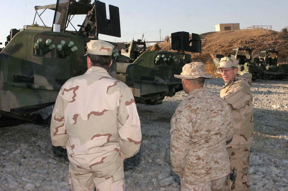 HADITHA DAM, Iraq (Jan. 3. 2005) - (From right) Chief of Naval Operations Adm. Michael Mullen, Maj. Joe E. Cleary, Dam Security Unit officer in charge and Master Chief Petty Officer of the Navy Terry D. Scott look at the rear of a Small Unit Riverine Craft used for operations here Jan. 3. The senior members of the Navy visited DSU in order to provide a smooth transition when the Navy takes over the unit from the Marines next spring. (Official Marine Corps photo by Lance Cpl. Sheila M. Brooks)