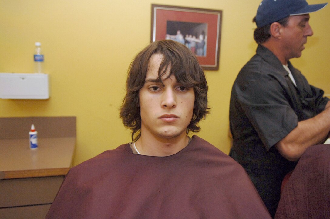 Pvt. Josiah Gulke anticipates a hair cut from barber Frank Sardina.