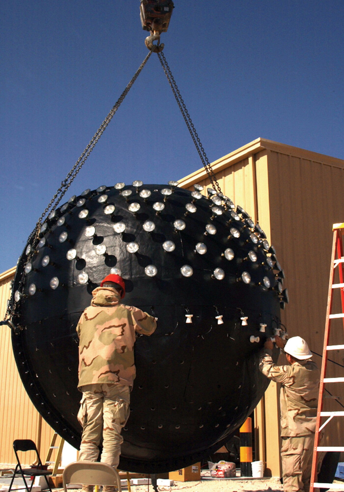 SOUTHWEST ASIA (AFPN) -- Airmen of the 379th Expeditionary Civil Engineering Squadron install lights into the New Year's Eve Ball they built. The ball has 417 lights. They built it in about 72 hours. It was suspended approximately 100 feet in the air and lowered from a crane as the crowd counted down the seconds until 2006.  The squadron's version of the Times Square tradition is larger and heavier than the New York version. (U.S. Air Force photo by Tech. Sgt. Sarah Webb)