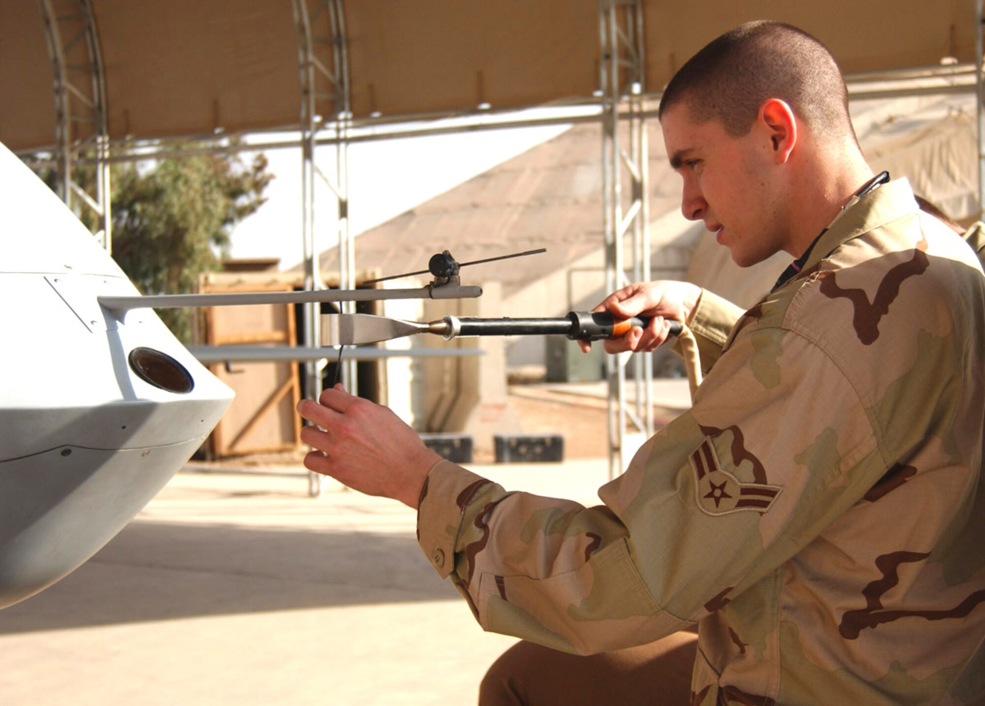 BALAD AIR BASE, Iraq (AFPN) -- Airman 1st Class Frank Miklos uses a heating tool to secure a yaw string on an MQ-1 Predator. The pilot uses the yaw string to determine wind direction. The Airman is with the 46th Aircraft Maintenance Unit and deployed from Creech Air Force Base, Nev. (U.S. Air Force photo by Staff Sgt. Tammie Moore)          