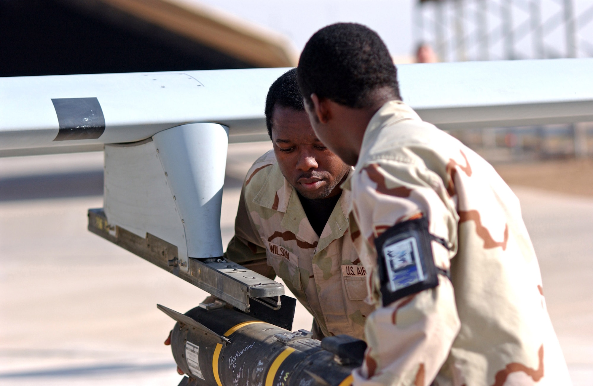 BALAD AIR BASE, Iraq (AFPN) -- (Left to right) Staff Sgt. Jwann Wilson and Staff Sgt. Bryan Larry, remove a Hellfire missile from an MQ-1 Predator after it returned from a mission. The sergeants, of the 46th Aircraft Maintenance Unit, do this so other unit maintainers can perform maintenance on the aircraft. They are deployed from Creech Air Force Base, Nev. (U.S. Air Force photo by Staff Sgt. Tammie Moore)