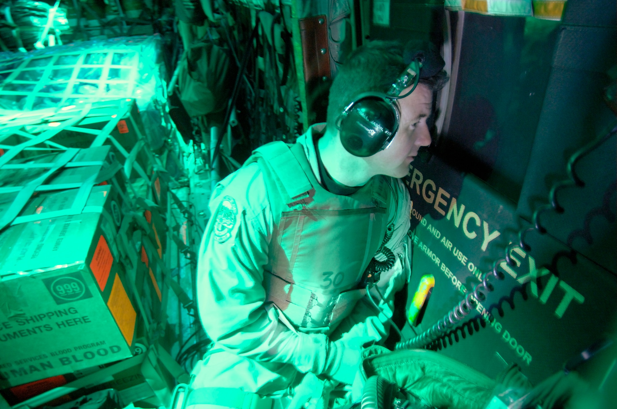 SOUTHWEST ASIA -- In the glow of a C-130 Hercules' cargo compartment, Staff Sgt. Jason Hall keeps an eye out the window for signs of an attack. The crew flew a New Year's Eve mission to deliver passengers and cargo. Members of the Air Force Reserve Command's 731st Airlift Squadron are ending their Southwest Asia tour. (U.S. Air Force photo by Master Sgt. Lance Cheung)