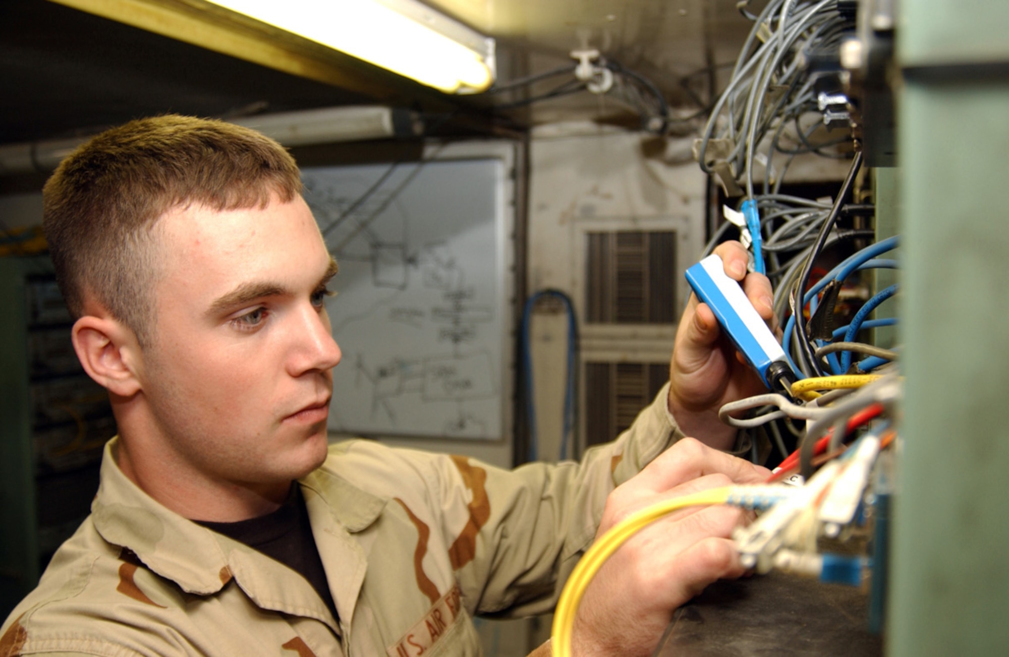 BALAD AIR BASE, Iraq (AFPN) -- Airman 1st Class Josh Green checks the wires on a system in the Kingpin communications tent. He is with the 727th Expeditionary Air Control Squadron. (U.S. Air Force photo by Senior Airman Bryan Franks)