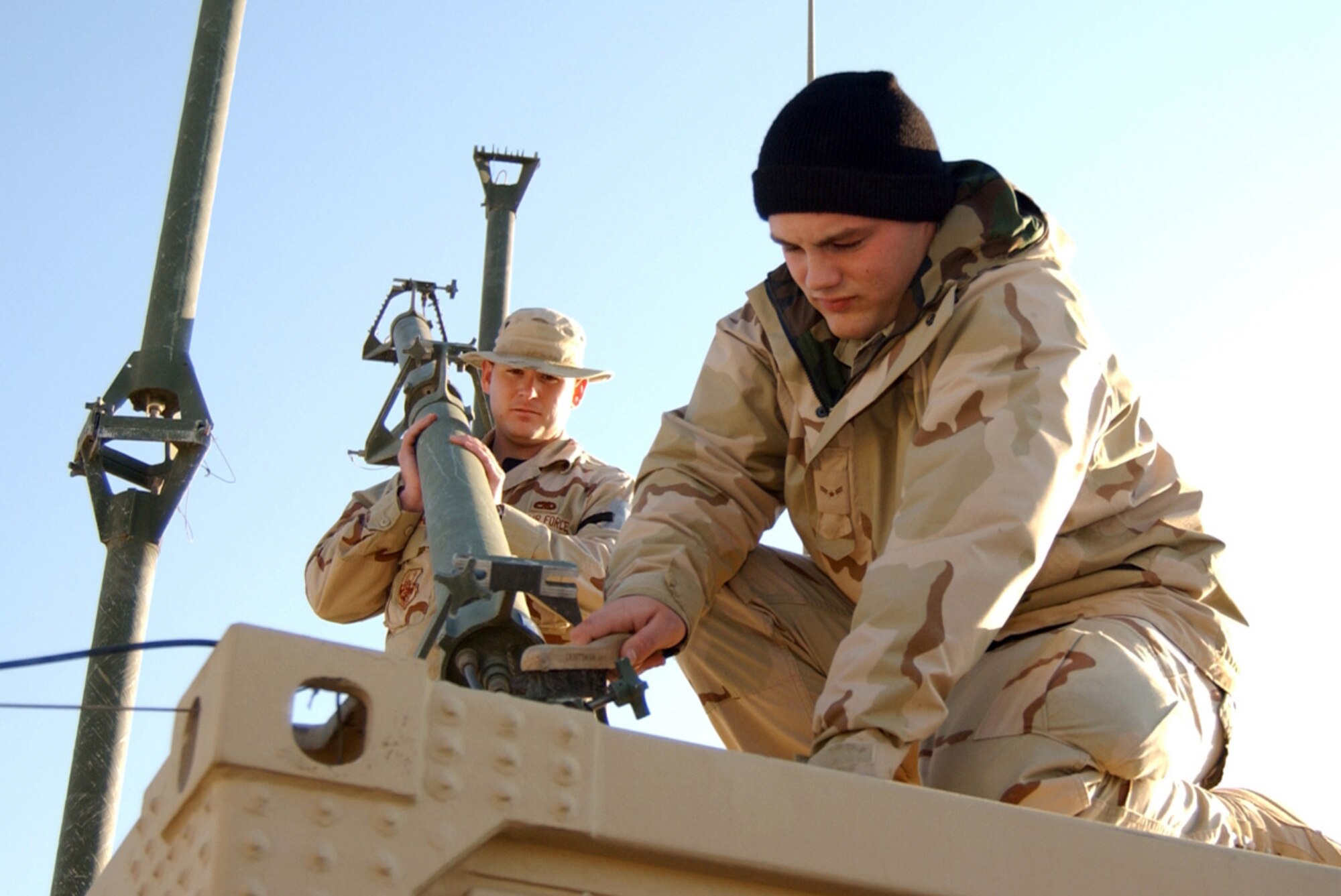 BALAD AIR BASE, Iraq (AFPN) -- Senior Airman Gil Stephens, left, holds an antenna as Airman 1st Class Sam Hauptly cleans it. Both Airmen are deployed to the 727th Expeditionary Air Control Squadron as ground radio technicians. (U.S. Air Force photo by Senior Airman Bryan Franks)