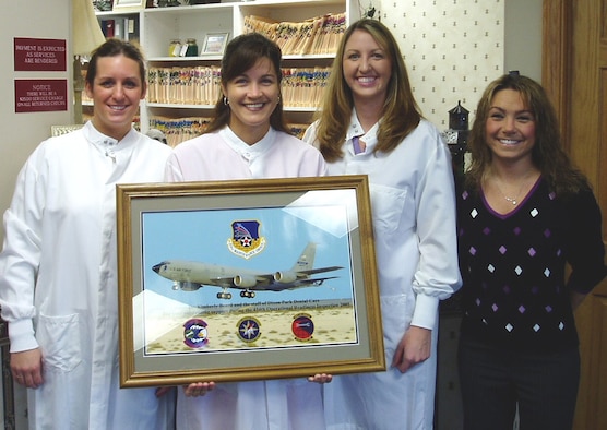 The members of a Kokomo, Ind., dentist's office proudly display a 434th ARW Lithograph.  From left to right: Ashlie Kinney, Dr. Kimberly Beard, Linsey Killian, and Trisha Wolfe.  The dentist and her staff provided support to a member of the 434th Air Refueling Wing who needed emergency dental work.