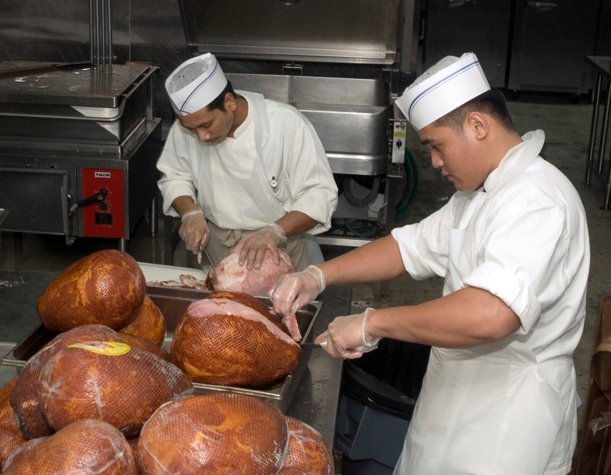 SOUTHWEST ASIA (AFPN) -- Dining facility chefs Sanu Bhai Bhujel (left) and Richard Sabiyan prepare hams at a 379th Air Expeditionary Wing dining facility at this desert base. (U.S. Air Force photo by Master Sgt. Stanley Coleman)