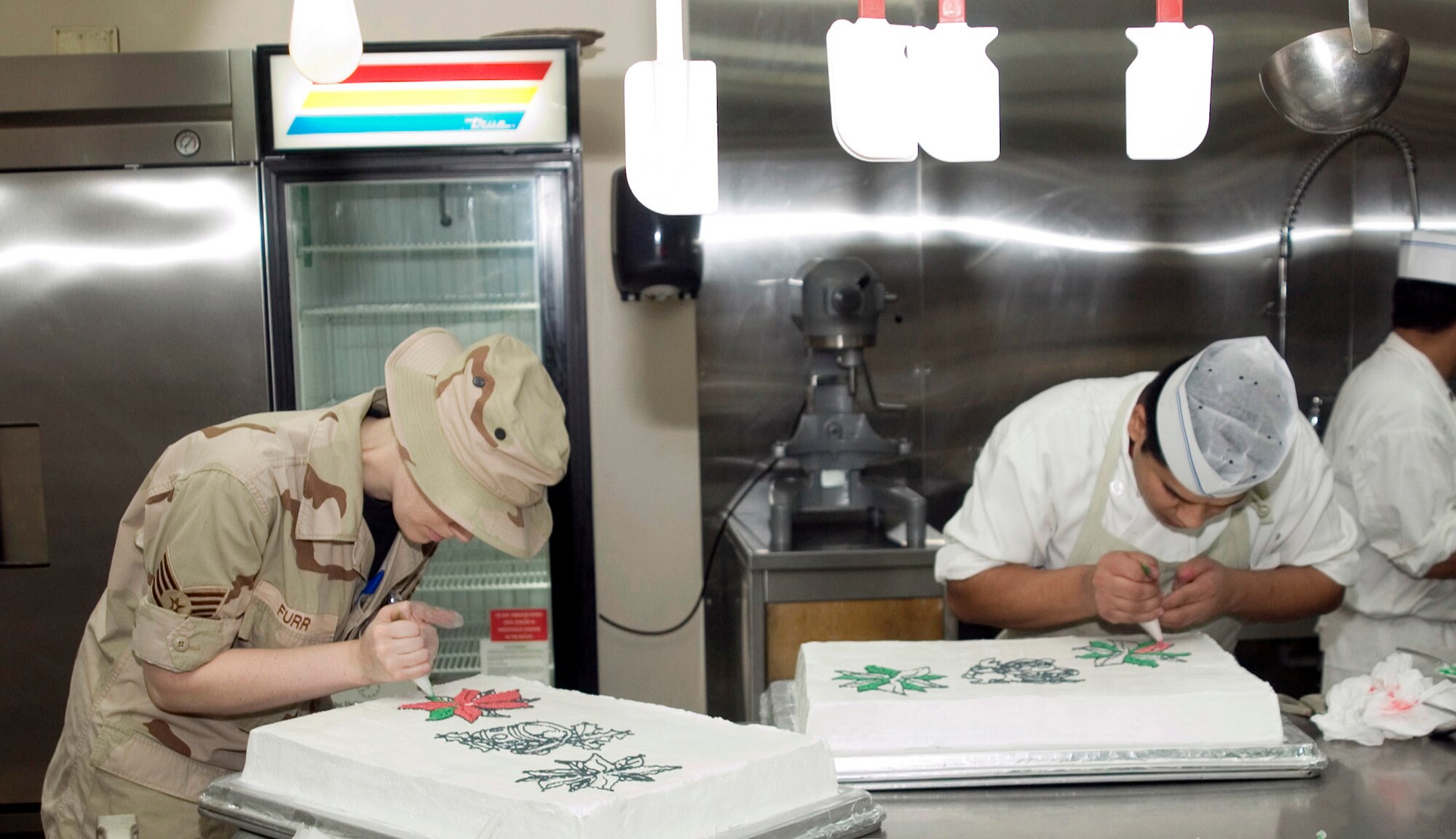 SOUTHWEST ASIA (AFPN) -- Quality assurance shift leader Staff Sgt. Darci Furr (left) helps master baker Puran Giri decorate cakes at a 379th Air Expeditionary Wing dining facility at this desert base. (U.S. Air Force photo by Master Sgt. Stanley Coleman)