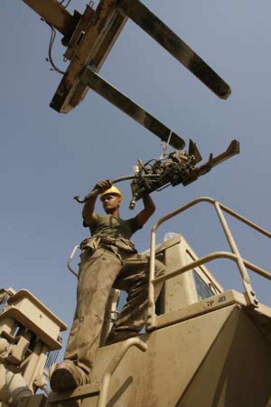 Communication is important for Lance Cpl. Gafatasi Napoleon, 19, from Pahoa, Hawaii, as he guides a forklift to replace a brake control valve on a giant hydraulic system used to move 40-foot containers July 4, 2006 at Camp Taqaddum, Iraq. The mechanics of Combat Logistics Regiment 15's Maintenance Company aren't celebrating today's holiday with barbeques and fireworks like many of their families are at home. The popular consensus is that it's no different than any other day here as they repair the heavy equipment and vehicles used to transport a steady stream of supplies to fellow Marines throughout the Al Anbar Province. Instead of dwelling on what they may be missing out on back home these Marines, part of the 1st Marine Logistics Group, stay focused on their mission. Official USMC photo by: Sgt. Enrique S. Diaz (060704-M-2864D-002) (Released)