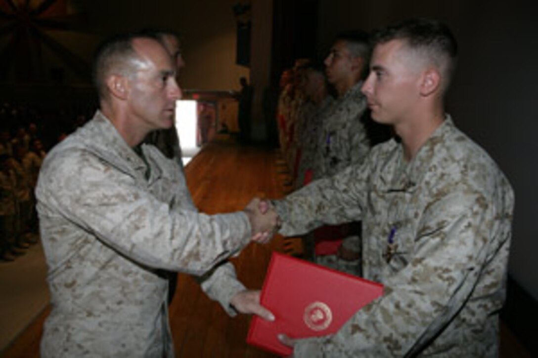 Col. Nicholas F. Marano, battalion commander of 1st Battalion, 7th Marine Regiment, shakes hands with Lance Cpl. Joel B. Mendham, a rifleman with Company C, 1/7, after awarding him the Purple Heart at the base theater Oct. 5.