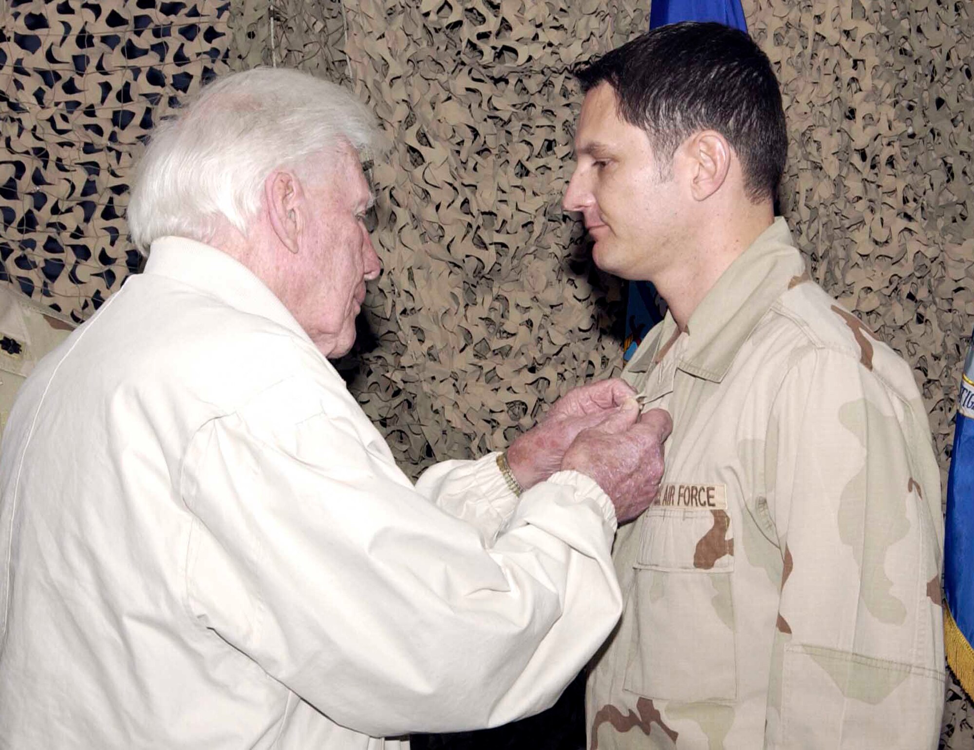 TRAVIS AIR FORCE BASE, Calif. (AMCNS) -- Robert Fearing pins a Bronze Star medal on his grandson, Special Agent Robert Fearing, Air Force Office of Special Investigations Detachment 303, during a ceremony here Dec. 2. Mr. Fearing, a former Marine, is also a Bronze Star recipient for heroic achievement while serving with a Marine tank battalion during a battle on Iwo Jima Volcano Islands in February 1945. (Photo by Luther Tolliver)
