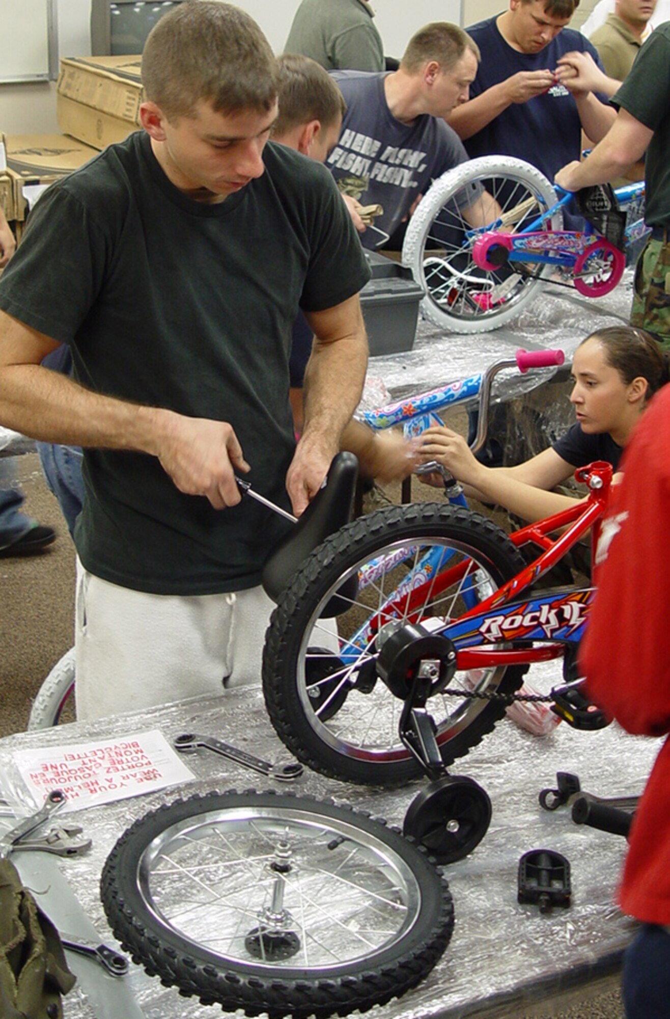 MCCONNELL AIR FORCE BASE, Kan. (AMCNS) -- Airman 1st Class Jeremy Biddle, 22nd Logistics Readiness Squadron, puts a small boy's bicycle together Nov. 30 as part of a volunteer effort in support of a local Marine Toys for Tots drive.