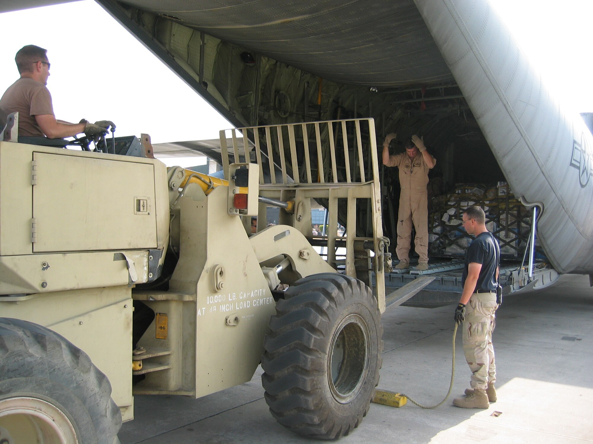 ISLAMABAD, PAKISTAN (AMCNS) – Tech. Sgt. Clay Baxter, 818th Contingency Response Group, drives a forklift up to a C-130 as Senior Master Sgt. Sid Mooney (center), Idaho Air National Guard, and Tech Sgt. Craig Moir, 818th CRG, spot him. (Photo by 1st Lt. Erick Saks)