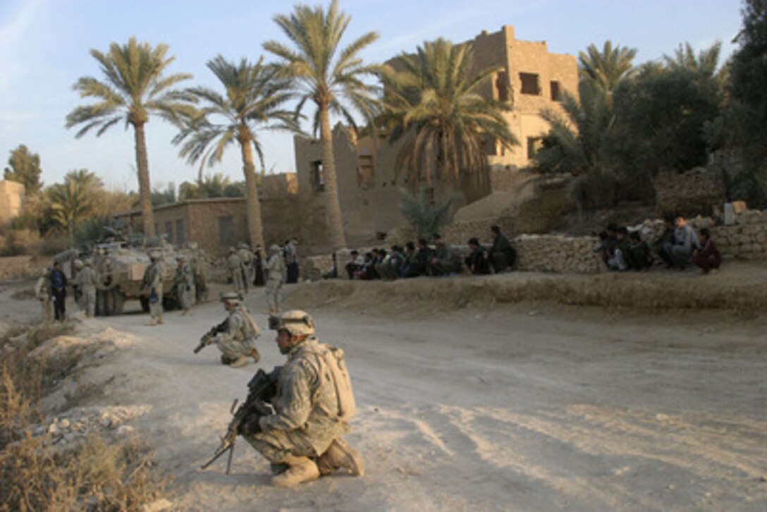 Soldiers of the U.S. Army's 2nd Battalion, 1st Infantry Regiment, provide security as their fellow soldiers talk to Iraqi men during a patrol in Rawah, Iraq, on Jan. 3, 2006. 