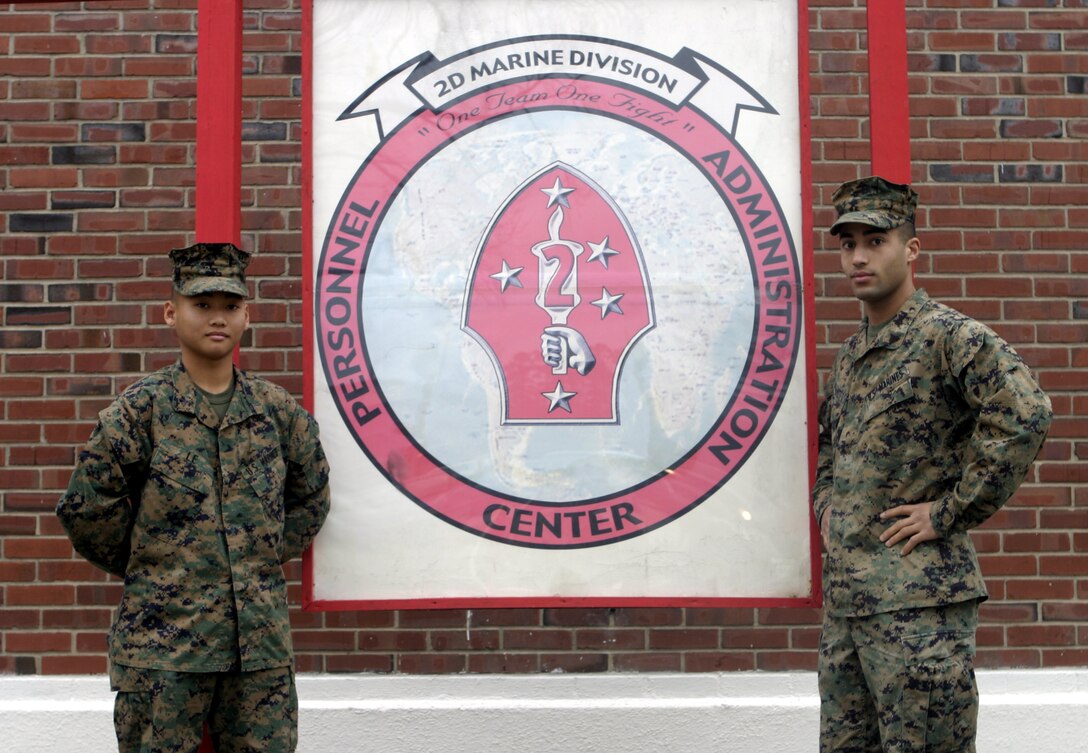 MARINE CORPS BASE CAMP LEJEUNE, N.C. - Corporal Jon Hoffmeier, right, and Pfc. Khang Le, left, two administration clerks with the 2nd Marine Division's Personnel Administration Center, proudly stand beside their unit's sign here Jan. 6.  The DPAC takes care of more than 18,000 Marines' administrative issues, such as paying appropriate allowances and keeping service record books current.  Recently, the DPAC Marines passed their Marine Corps Administrative Analysis Team (MCAAT) inspection, during which a team of personnel appointed by Headquarters Marine Corps evaluated the shop's timeliness and accuracy in paying the Division's leathernecks their allowances.