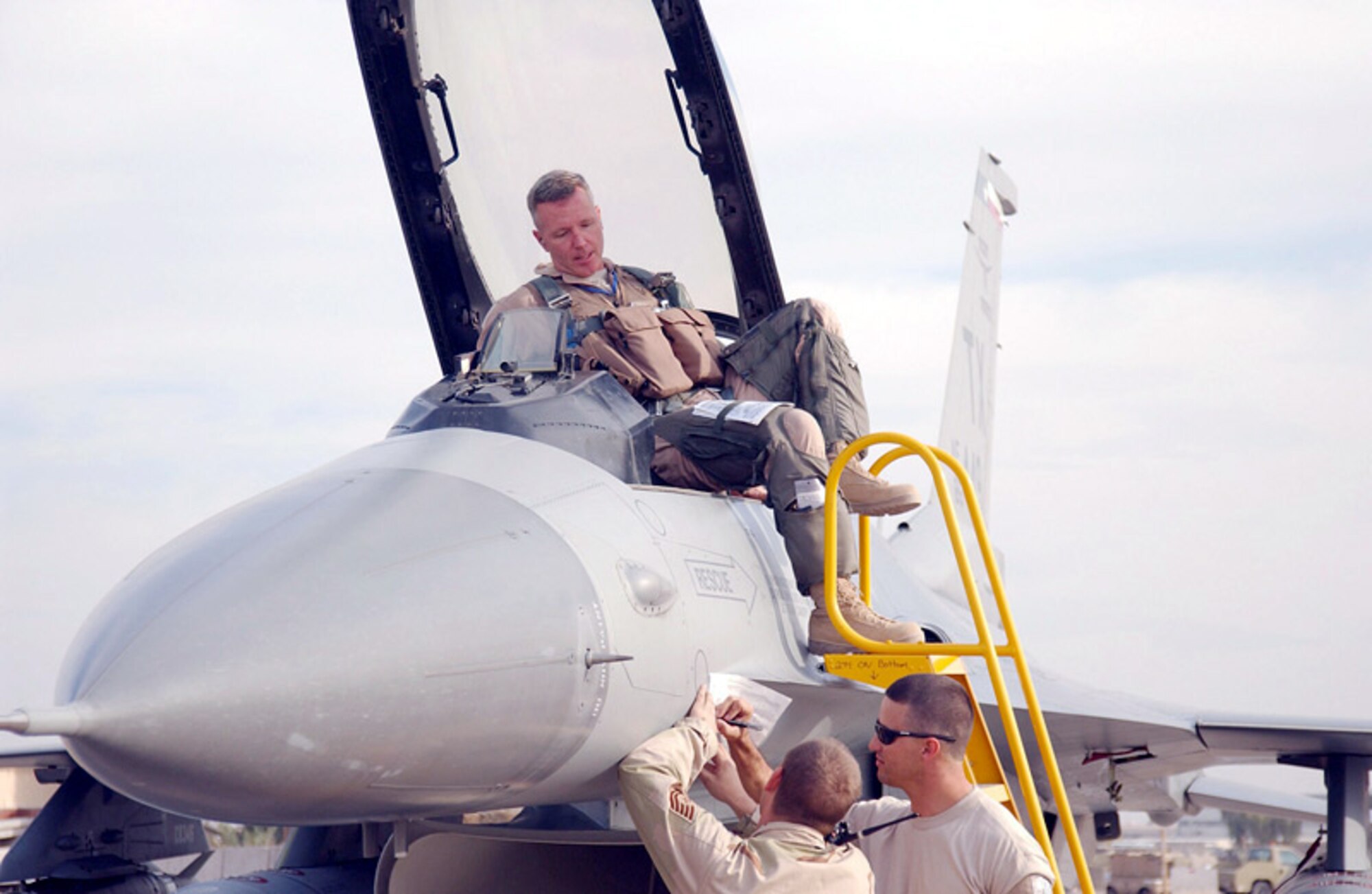 BALAD AIR BASE, Iraq - Col. William "Blaze" Binger, 332nd Expeditionary Operations Group deputy commander, climbs out of an F-16 fighter aircraft shortly after breaking his 4,000 flying hours milestone, as Tech. Sgt. Denver McCullough (left) and Staff Joe Lester, both F-16 crew chiefs from the 332nd Expeditionary Aircraft Maintenance Unit (Tiger Maintenance), annotate post-flight information on the aircraft forms.  Colonel Binger is only the 10th person in the world to accomplish such a feat in an F-16.  Colonel Binger is deployed to Balad Air Base, Iraq, from the 944th Fighter Wing, Luke Air Force Base, Ariz. (Air Force photo by Tech. Sgt. Pamela Anderson)