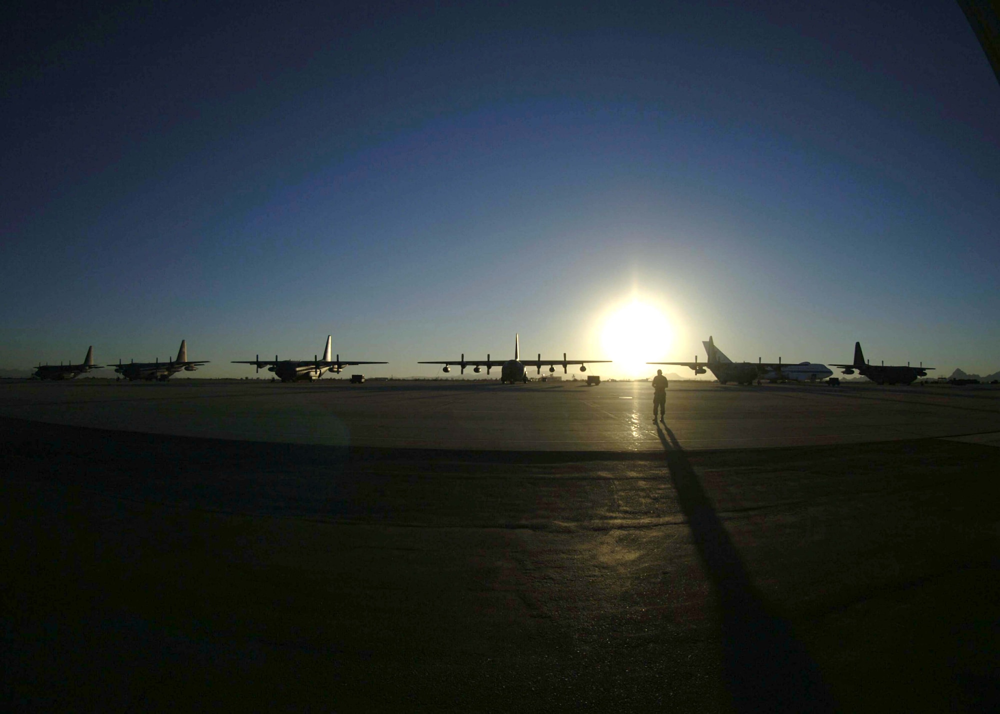 DAVIS-MONTHAN AIR FORCE BASE, Ariz. (AFPN) -- A crew chief with the 563rd Maintenance Squadron walks toward a fleet of C-130 Hercules aircraft at sunset here. (U.S. Air Force photo by Airman 1st Class Christina D. Ponte)
