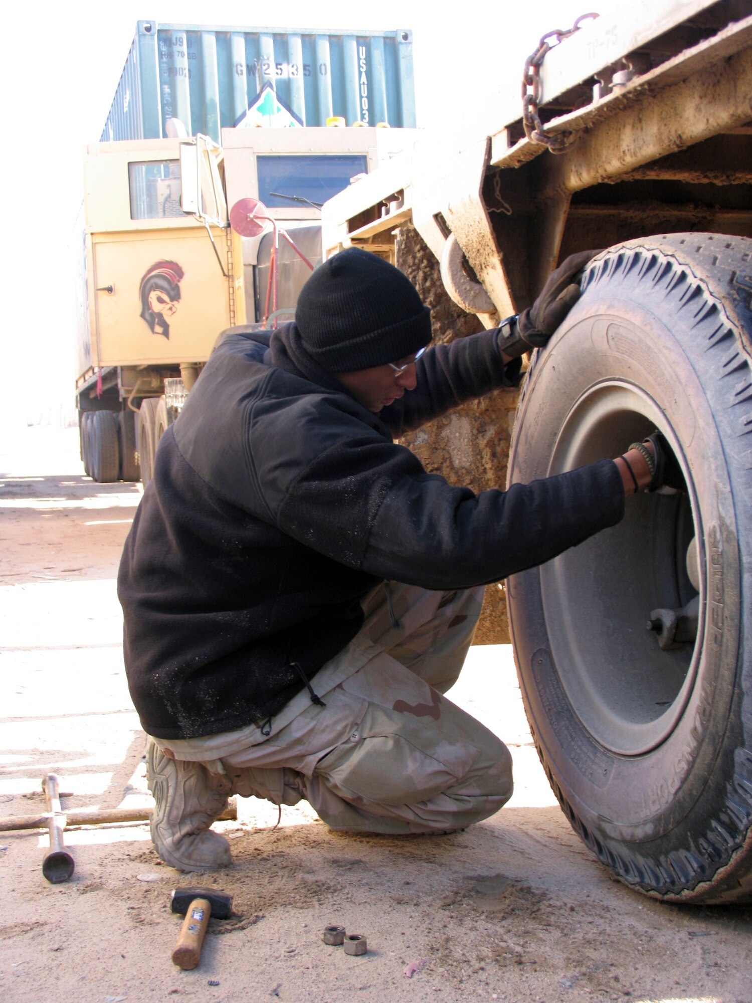 SOUTHWEST ASIA (AFPN) -- Vehicle operator Senior Airman Johari Ginocchio removes the lug nuts from one of his truck's tires that went flat on the road to Iraq. (U.S. Air Force photo by Staff Sgt. Scott Campbell)