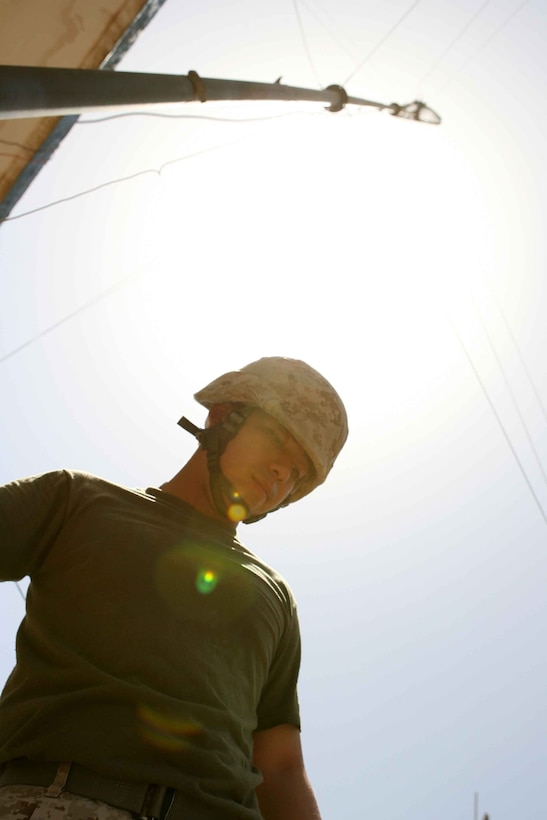 Cpl. Lissay Ly with the 1st Marine Logistics Group's Communications Company walks beneath a communication antenna at Camp Habbiniyah, Iraq. The antenna was set up May 6, 2006 in order to give Military Transition Teams secure communication. Official USMC photo by:  Cpl. Stephen Holt