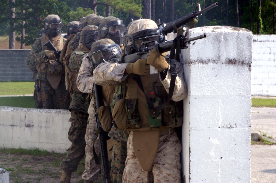 Lance Cpl. William C. Michener, a field artilleryman with 3rd Battalion, 10th Marine Regiment, and the rest of his squad post against a wall before entering a building at the military operations on urban terrain facility here, June 5.  Michener and his battalion were trained in basic infantry tactics in urban environment during the five-day exercise.