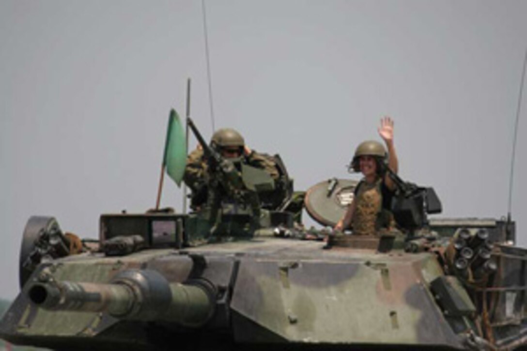 060906-M-3944Z-001 - The wife of a Marine from 2nd Tank Battalion, 2nd Marine Division, waves from the gunner's turret of an M1A1 Abrams tank here June 9. The woman was participating in the unit's Jane Wayne Day, an annual event designed to give the wives of Marines an idea of the daily life of their husband. The wives were able to shoot the service pistol and rifle, ride in a tank and amphibious assault vehicle, and get hands on with static displays of machine guns, tank extractors, and other equipment used in the daily life of a Marine.