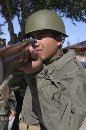 Lance Cpl. Jesus Ramirez, representing a Marine from the Korean War, stares down the sights of an Enfield rifle.