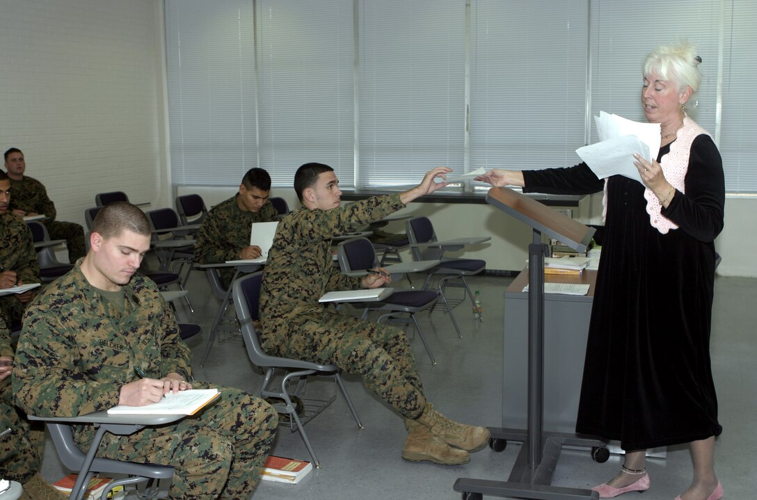 MARINE CORPS BASE CAMP LEJEUNE, N.C. - An instructor with Coastal Carolina Community College hands Marine students some assignments back during a lunchtime class at the John A. Lejeune education center here.  Active-duty military members are eligible to receive apprenticeship completion certificates, along with 100 percent tuition assistance for taking classes on the base campus, through postal correspondence and various universities online.  Personnel may speak with a counselor aboard the Lifelong Learning Center here to discuss their higher learning goals and look into off-duty educational opportunities here and while overseas.