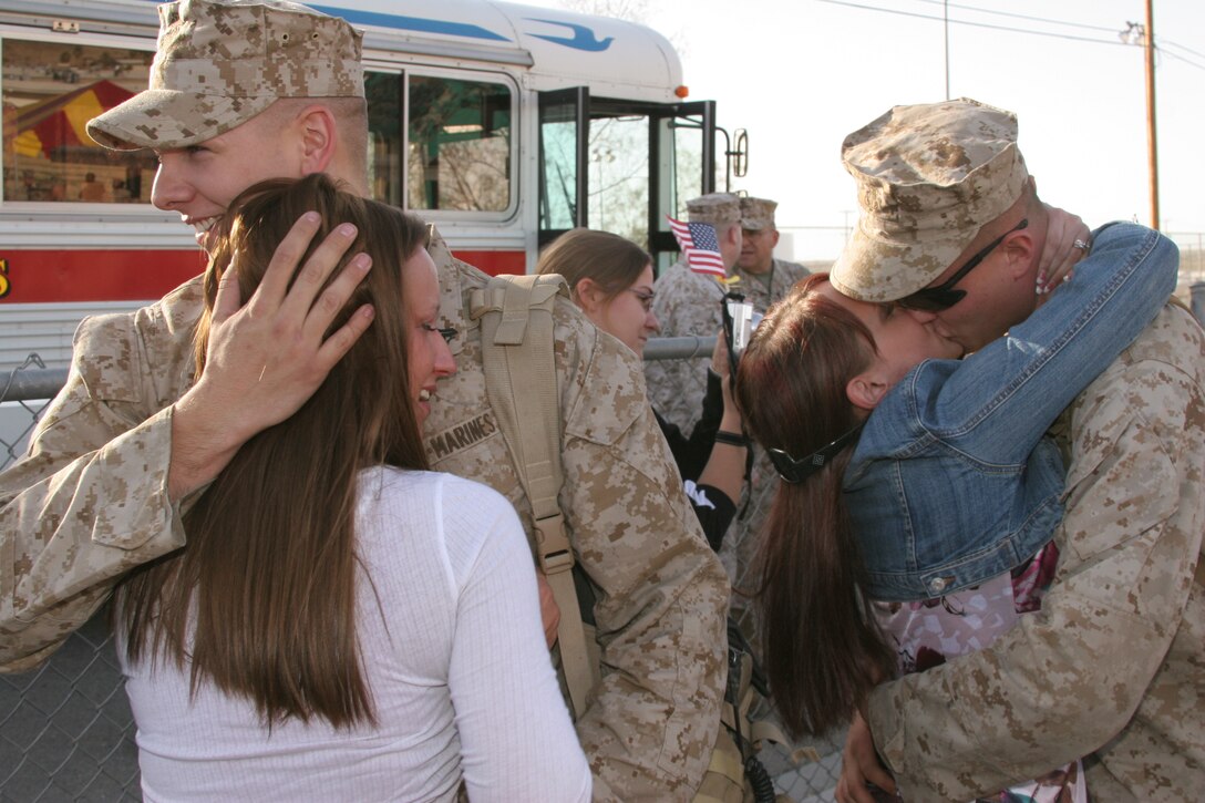 Marines with 2nd Battalion, 7th Marine Regiment?s advance party embrace and kiss their wives as they reunite with each other Jan. 11 on the Combat Center?s Victory Field.
