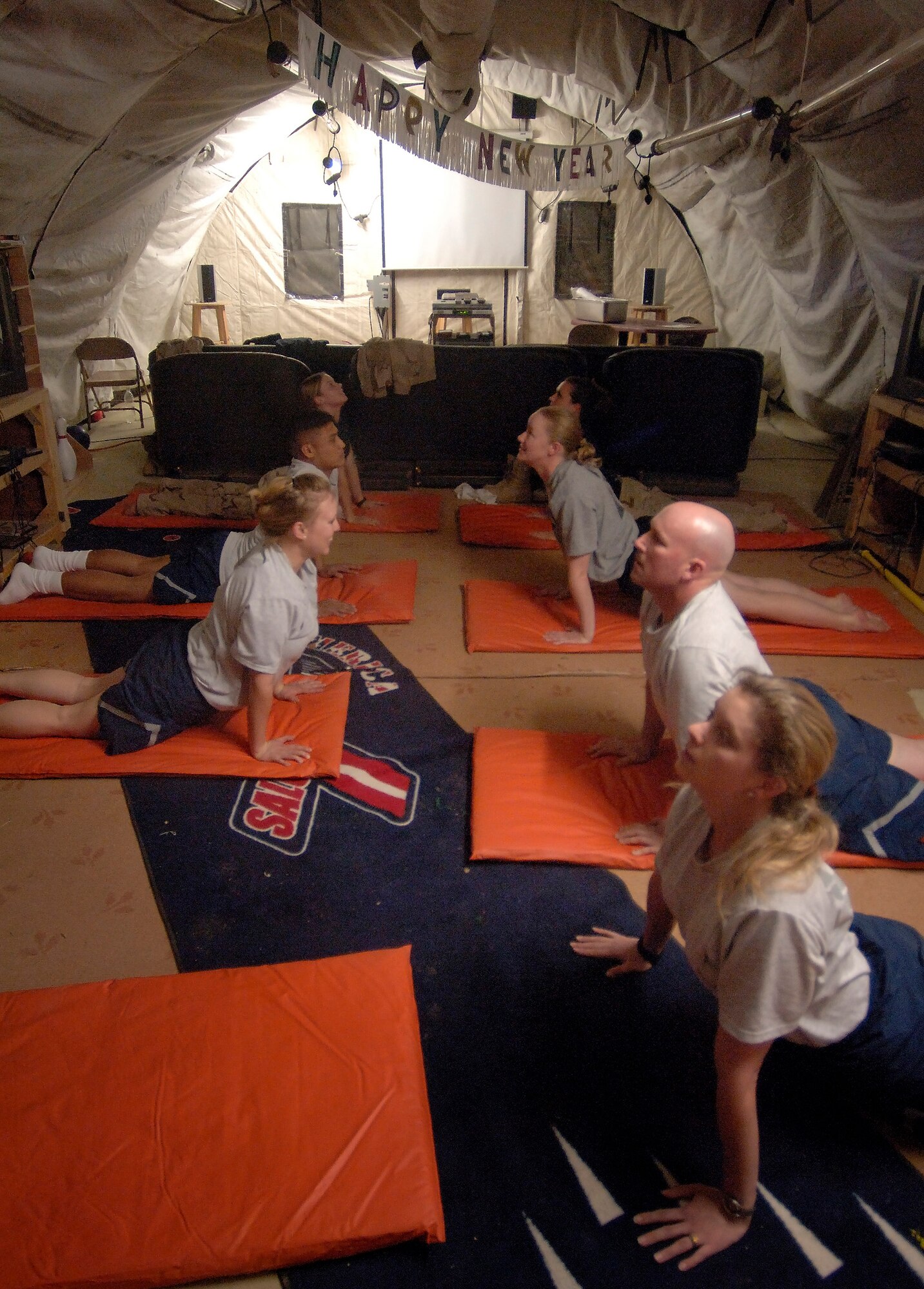 BALAD AIR BASE, Iraq (AFPN) -- Staff Sgt. Bonnie McKinley (left) leads Airmen and Soldiers in a yoga class during a break in her 15-hour shift at the Air Force Theater Hospital here. The 5-foot-4-inch respiratory therapist with the 332 Expeditionary Medical Group weighs 140 pounds. But, a few years ago, she weighed 215 pounds after a pregnancy. She attributes her weight loss and fitness increase to the practice of yoga and a healthy diet. She is deployed from Sheppard Air Force Base, Texas. (U.S. Air Force photo by Master Sgt. Lance Cheung)